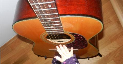 Dieses Bild zeigt eine Kinderhand an einer Gitarre