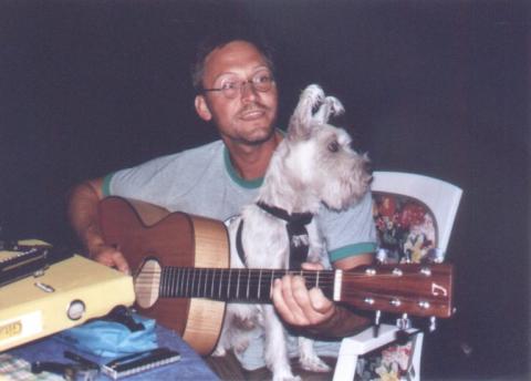 Peter mit Gitarre und einem Hund auf dem Schoß